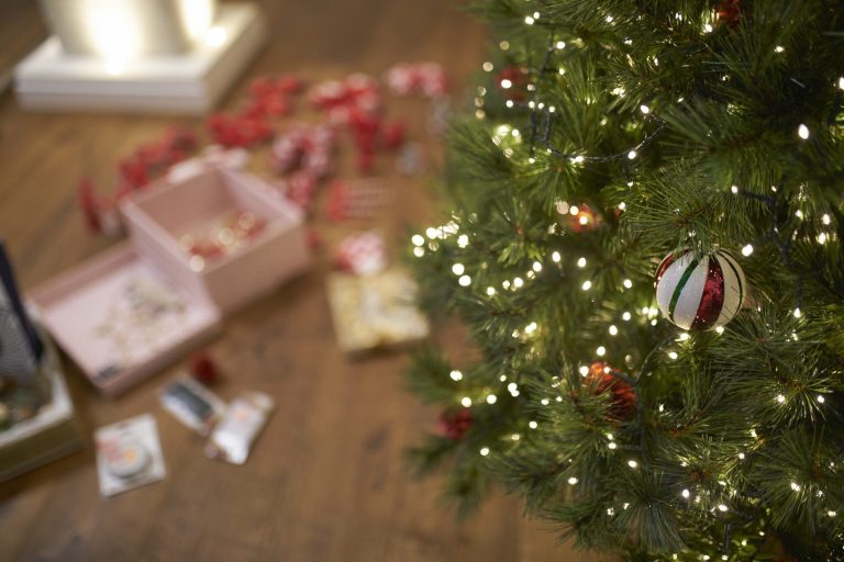 Close-up of Christmas bauble on tree with lights.