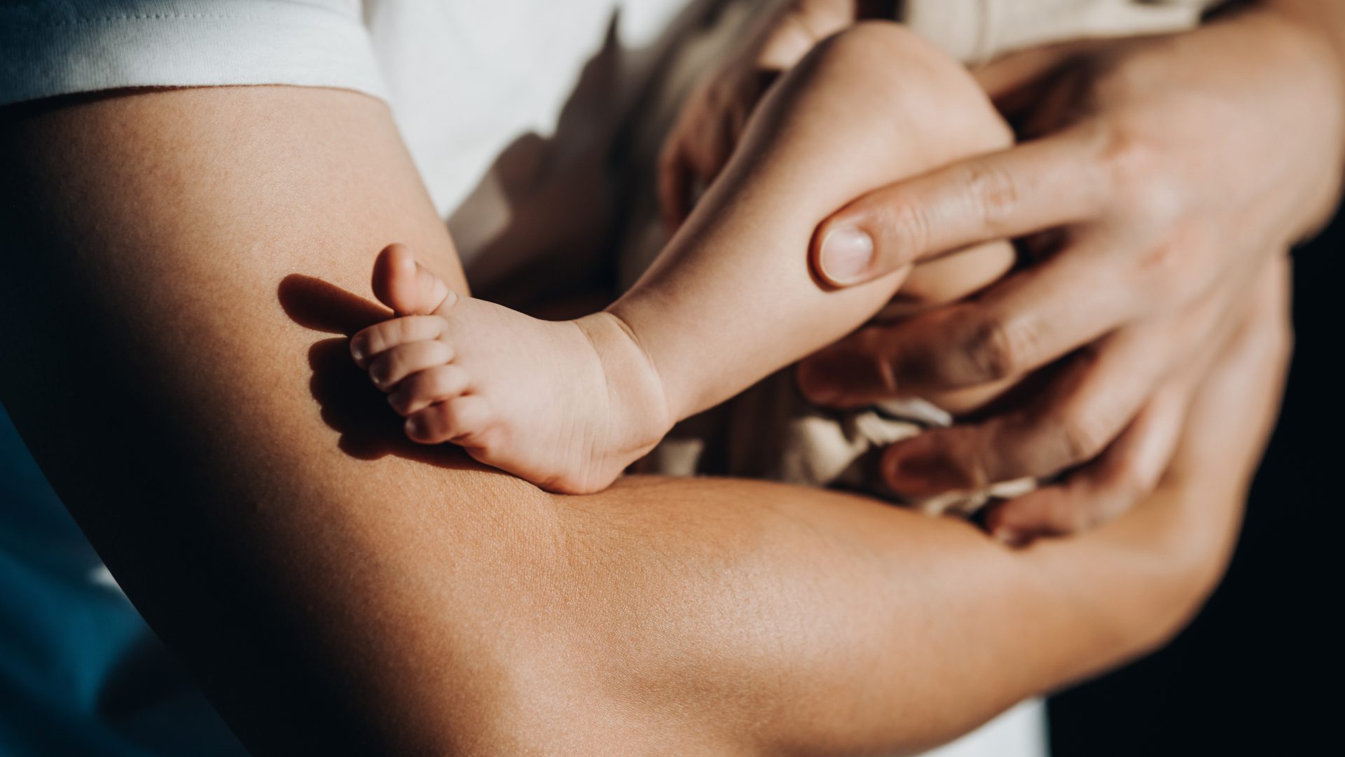 Close up of a loving young Asian father carrying his newborn baby daughter in arms. Bonding moment of father and daughter. Fatherhood. Skin to skin contact. Love, care and tenderness